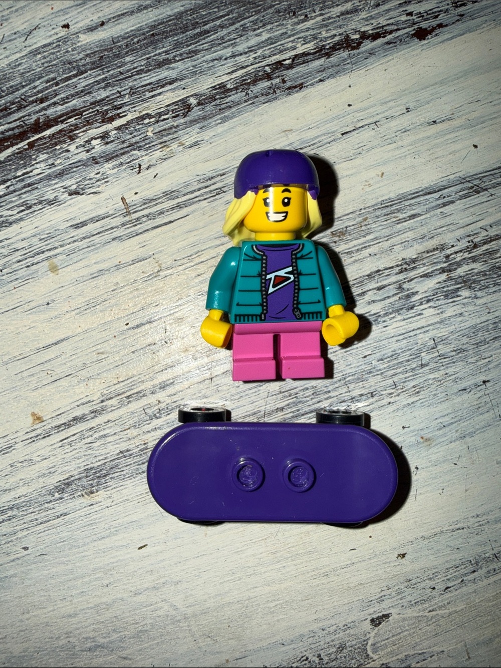 Lego Female Minifigure in Teal Jacket with Purple Hat and Purple Skateboard